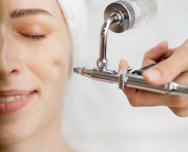 Young woman receiving oxygen mesotherapy on her face, close-up view from above. Concept of non-invasive and revitalizing skin treatment